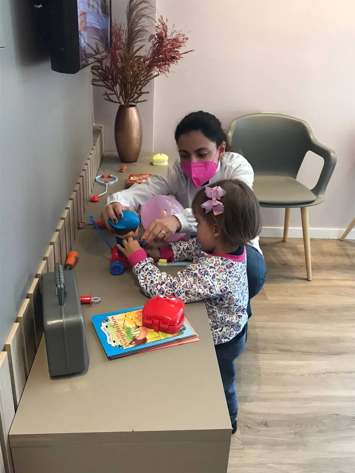 Foto da Dra Luciana com paciente da Clínica Aurora, sendo uma criança, menina, brincando.